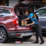 Amazon delivery driver loading a package into a customer's vehicle