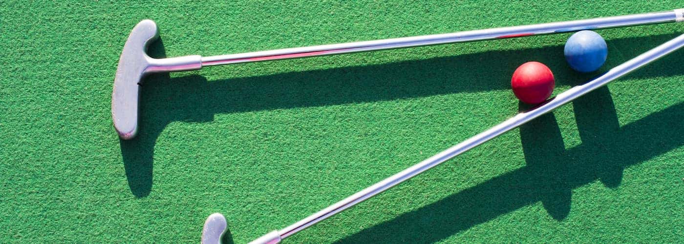 close up of mini golf clubs and mini golf balls on green