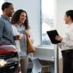 A man and woman interacting with a female employee at a Chevrolet dealership - Graff Chevrolet in Grand Prairie, Texas