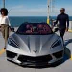 A man and woman next to a silver 2021 Chevrolet Corvette - Graff Chevrolet in Grand Prairie, Texas