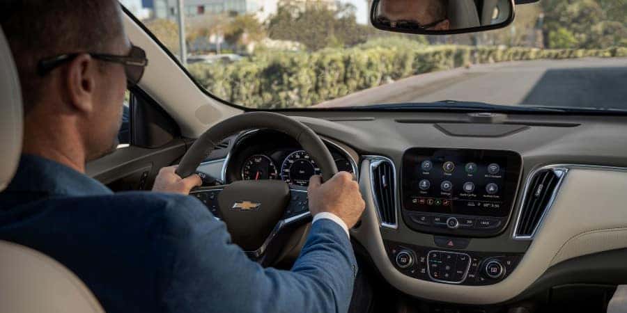 A man wearing sunglasses while driving a 2019 Chevrolet Malibu | Graff Chevrolet in Grand Prairie, Texas