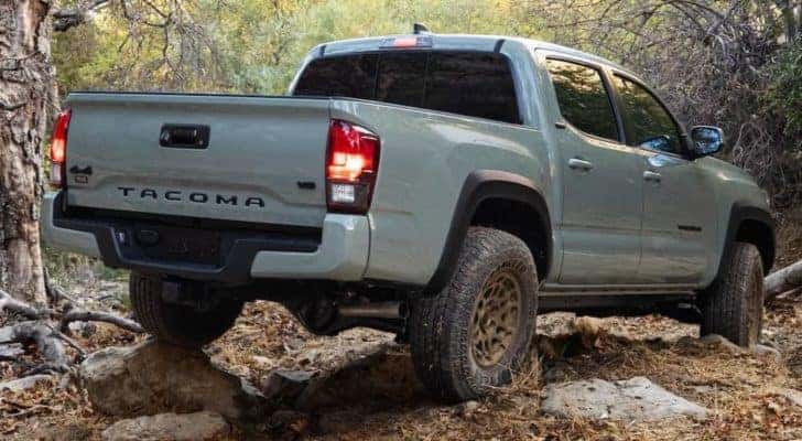A grey 2022 Toyota Tacoma SR5 Double Cab is shown from a rear angle off-roading on a muddy trail.