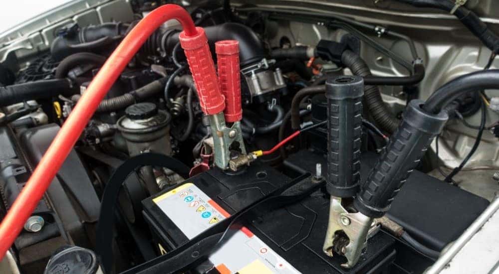 A close up shows jumper cables attached to a battery.