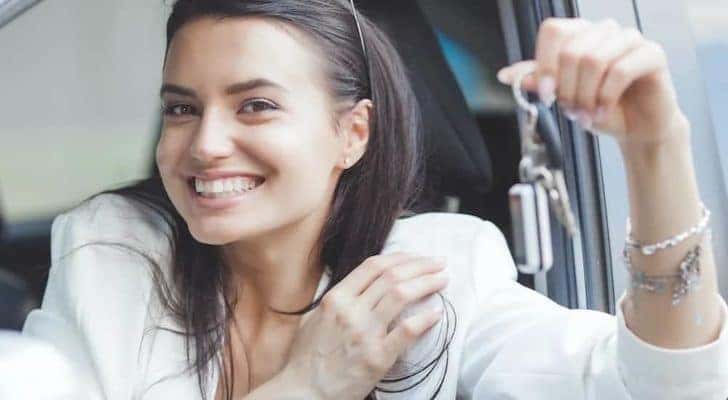 A person is shown smiling and holding a car key.