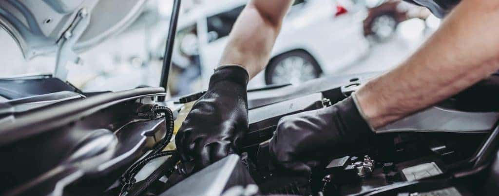 A mechanic is shown working on a vehicle's engine.