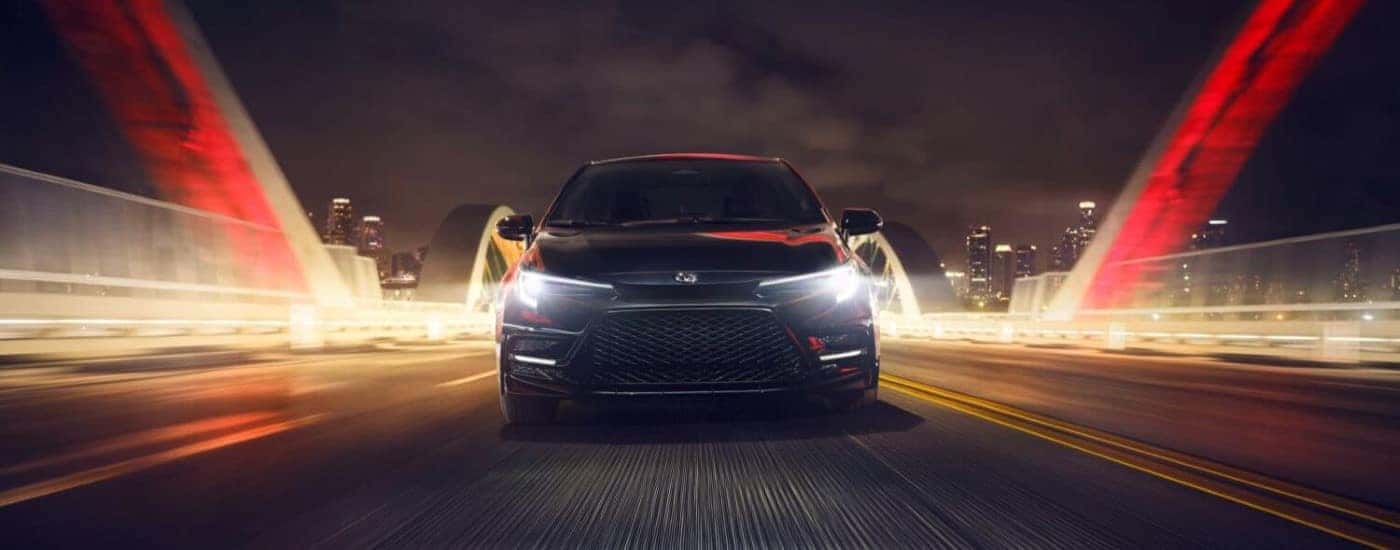 A rear view of a black 2024 Toyota Corolla Nightshade driving over a bridge from a Toyota dealer near Mechancisville.