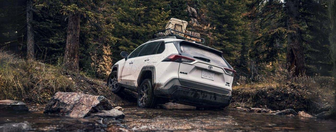 A rear view of a white 2024 Toyota RAV4 TRD driving off-road.