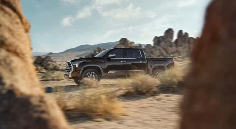 A dark brown 2023 Toyota Tundra 1794 is shown from the side off-road.