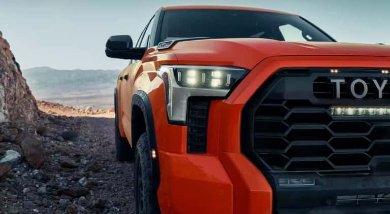 An close-up shows the headlight on a orange 2023 Toyota Tundra TRD Pro.