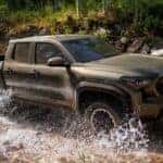 A green 2025 Toyota Tacoma TRD Off-Road is shown driving through a stream.