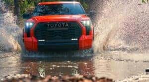 An orange 2022 Toyota Tundra TRD Pro is shown splashing through a creek.