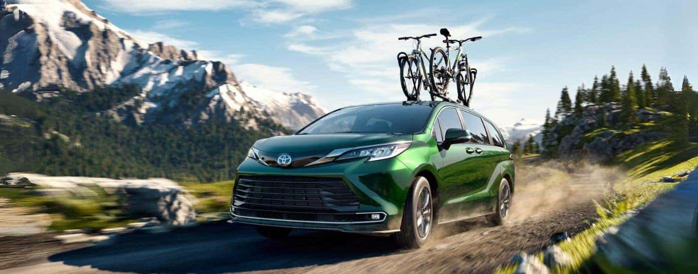 A green 2024 Toyota Sienna Limited driving on a dirt road with bikes on the roof.