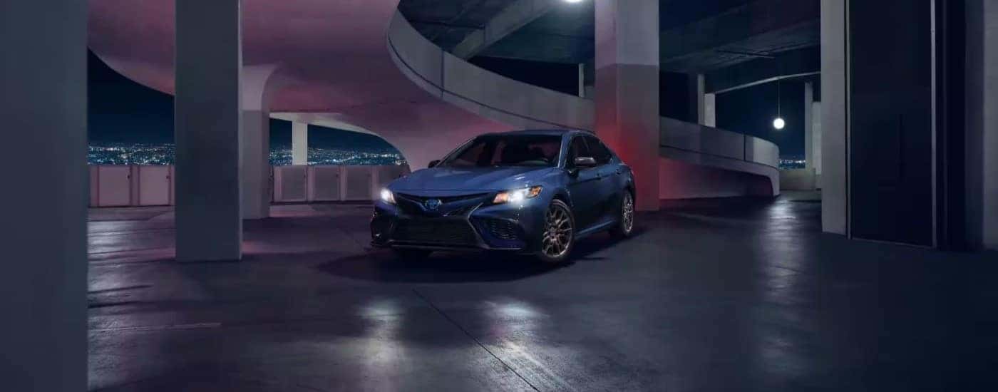 A blue 2024 Toyota Camry driving in a parking garage.