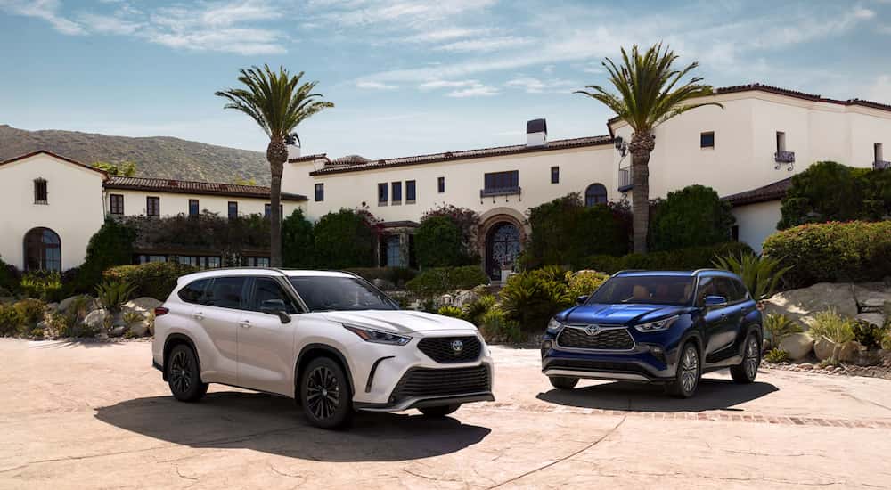 Two 2026 Toyota Highlander's for sale parked in front of a home. 