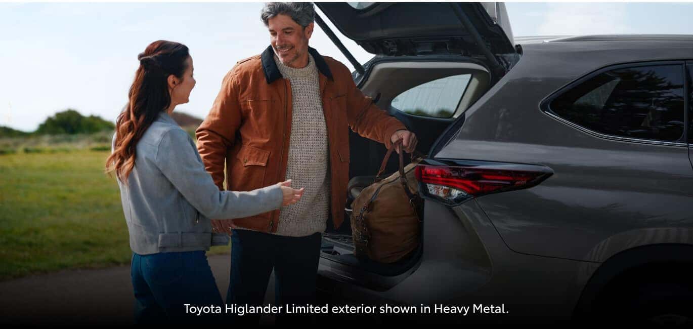 Close-up rear view of a Toyota Highlander Limited with open liftgate as a couple loads luggage.