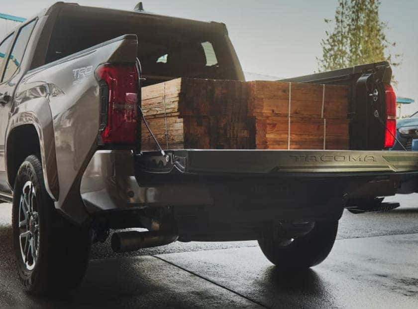 Toyota pickup truck with its tailgate lowered and bed loaded with stacked lumber.