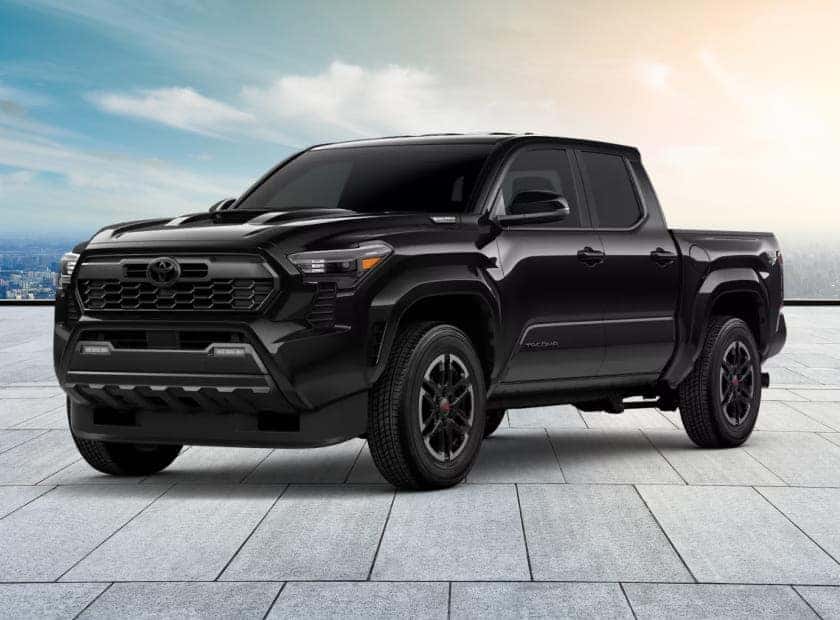 Black Toyota Tacoma pickup truck shown from a front three-quarter view against a city skyline.