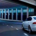 2019 Jaguar XE in white driving under bridge