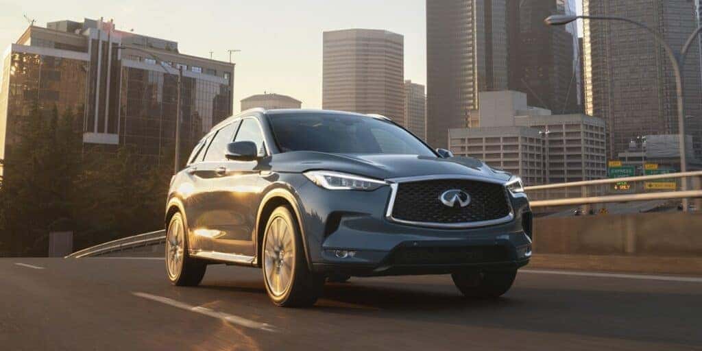 Grey 2024 INFINITI QX50 driving down a city street