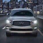 Silver 2024 INFINITI QX80 driving down a city street