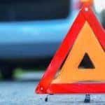 Changing the tire on a broken down car on a road with red warning triangle