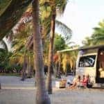 Exterior of Mercedes-Benz Airstream Tommy Bahama Relax Edition open on beach with campers