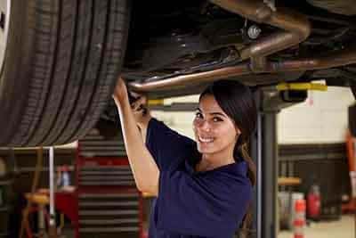 Female auto mechanic checking car tire