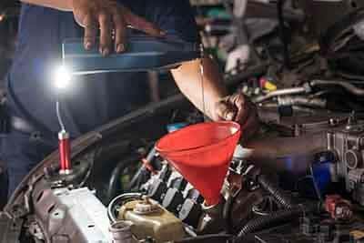 Mechanic adding engine oil to car
