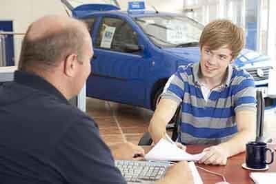 Young man filling in paperwork in car showroom