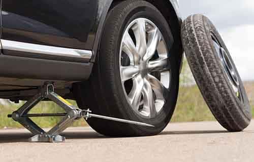 Spare tire leaning up a car thats jacked up