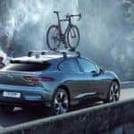 2019 Jaguar I-PACE driving on mountain bridge with roof-mounted bicycle