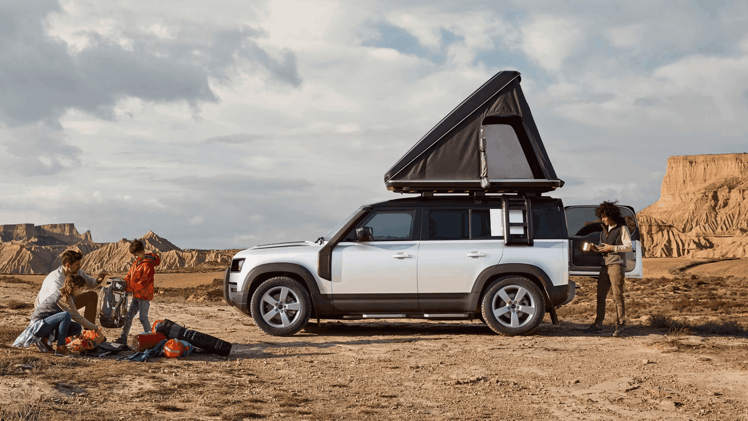 family using the Defender 110's camping accessories to camp outdoors