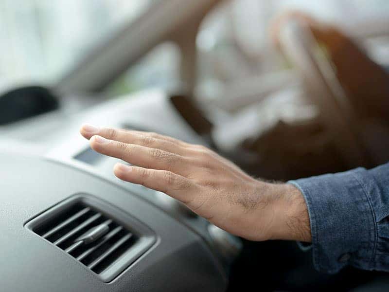 Holding hand over a car air vent.