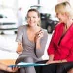 car salesman handshaking with cheerful young buyer