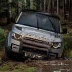 Defender driving through muddy water in forest
