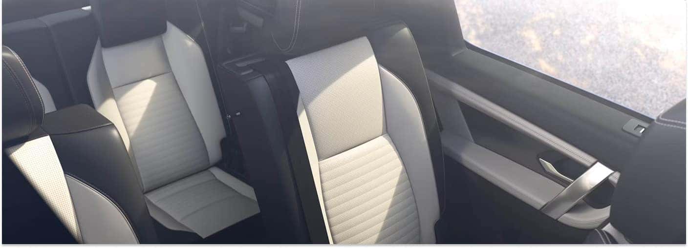 An elevated interior view of the 2026 Discovery Sport showcasing the rear seating cabin with two-tone black and white upholstered seats.
