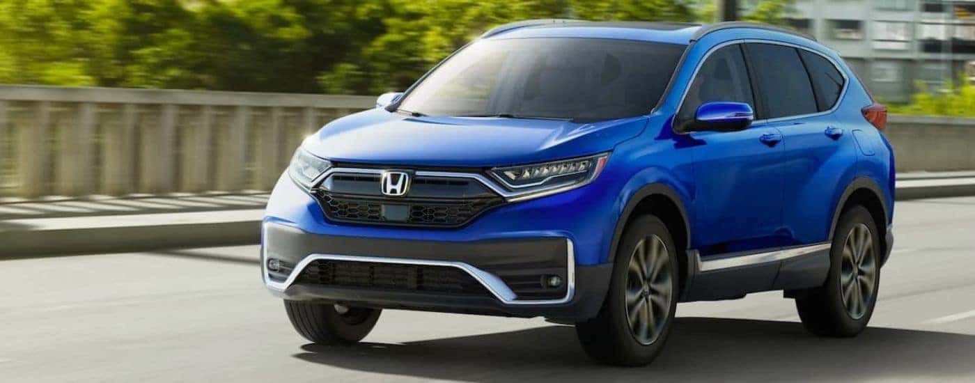 A blue 2021 Honda CR-V Touring driving to see a used Honda for sale.