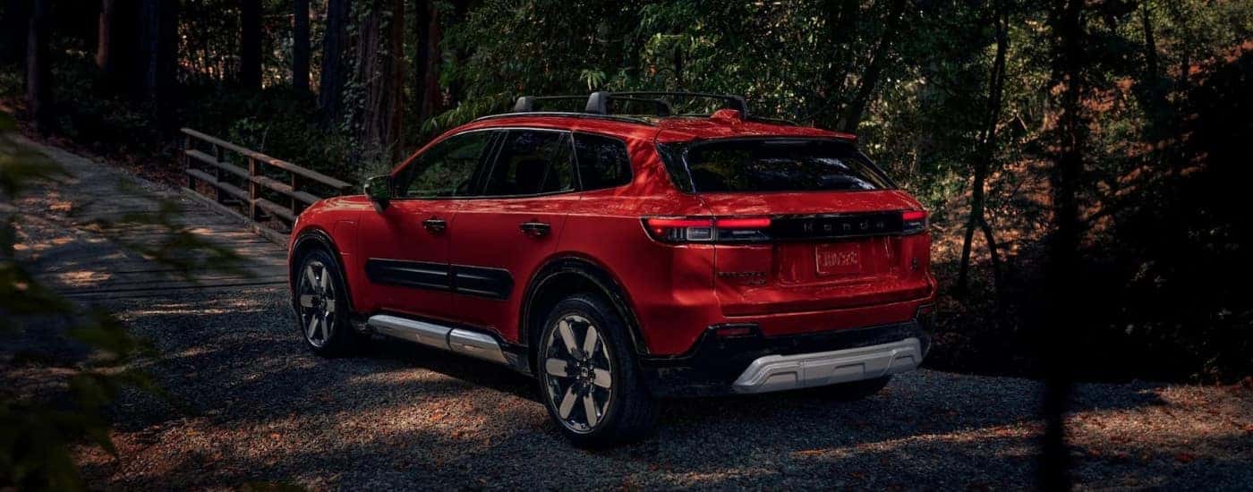 A red 2024 Honda Prologue Elite is shown on a tree-lined trail.
