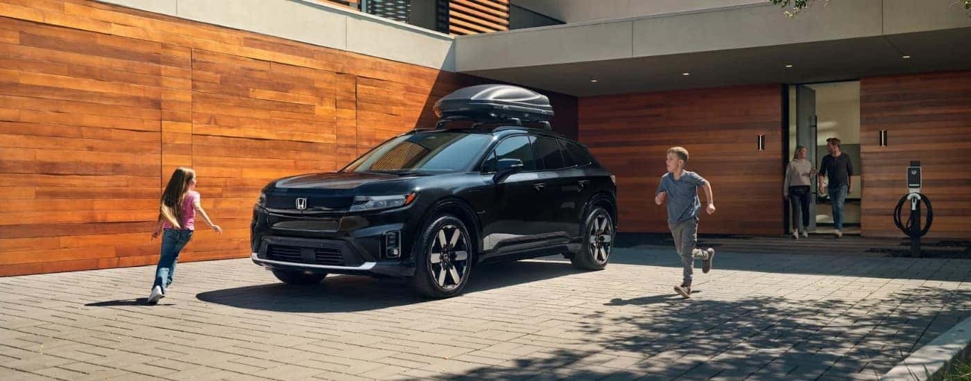 People are shown running around a black 2024 Honda Prologue Elite.