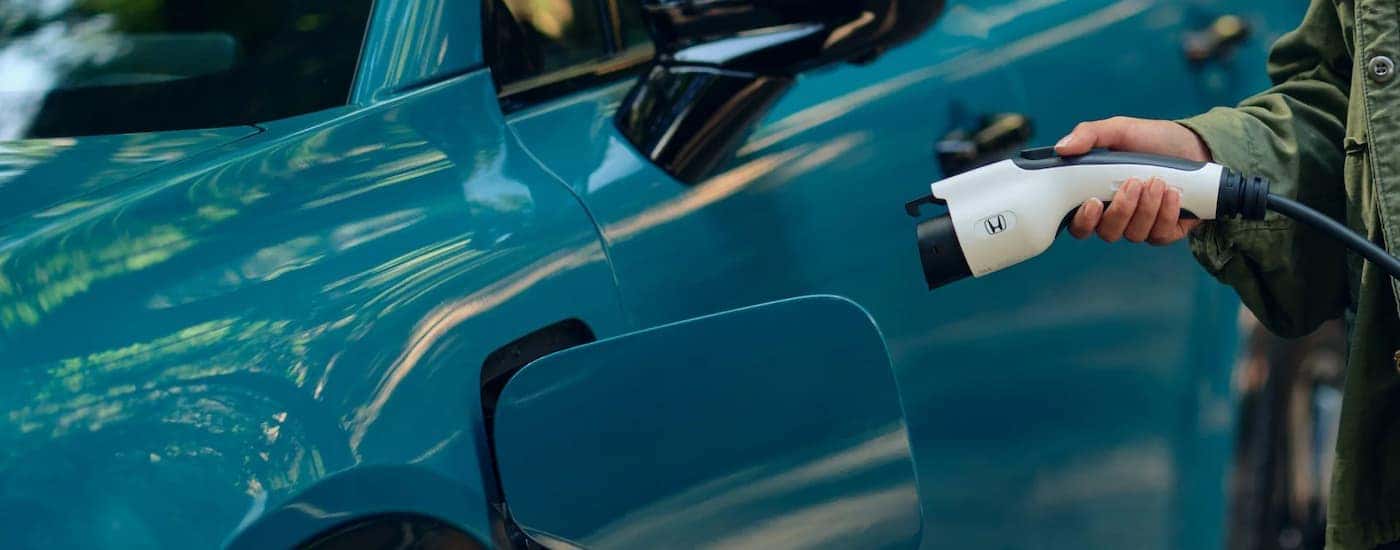 A close up of a Honda EV for sale charging, a blue 2025 Honda Prologue Elite.