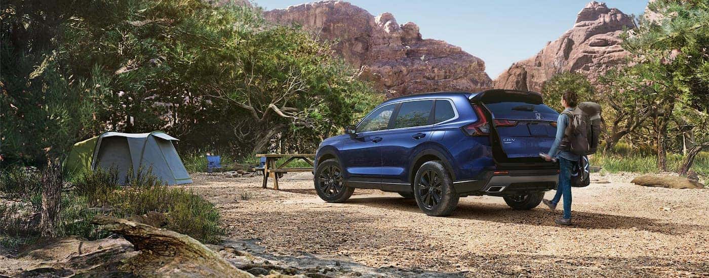 Rear view of a blue 2025 Honda CR-V Sport Touring parked by a camp.