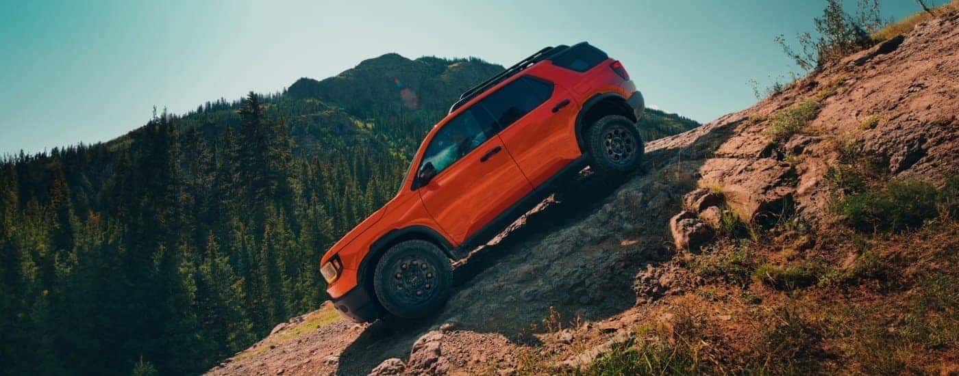 An orange 2026 Honda Passport TrailSport Elite is shown driving to a Honda dealer near Hartford.