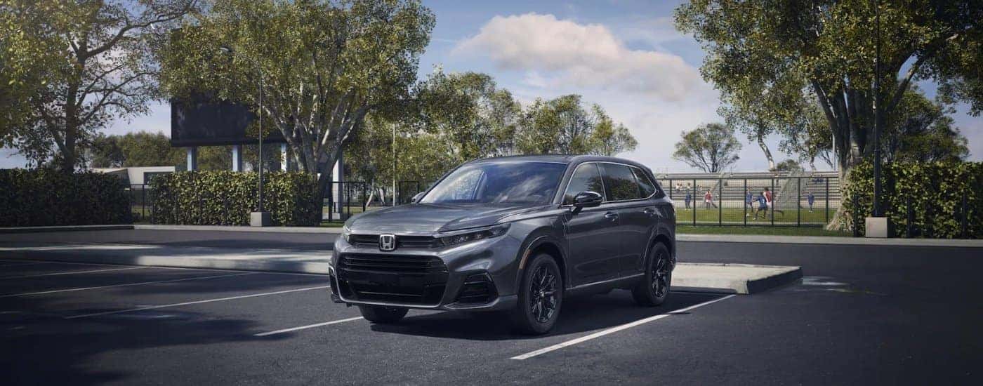 A grey 2025 Honda CR-V eFCEV is shown parked near a sports field.