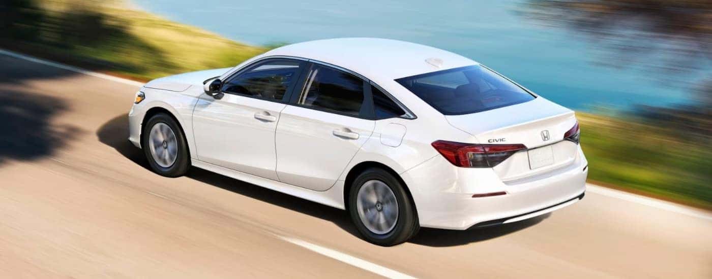 A white 2025 Honda Civic LX is shown driving to a Honda dealer near Windsor.