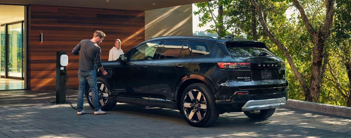 A black 2025 Honda Prologue charging in a driveway