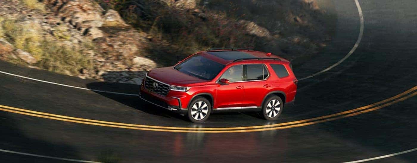 A red 2025 Honda Pilot driving on a highway from a dealer near Rockville