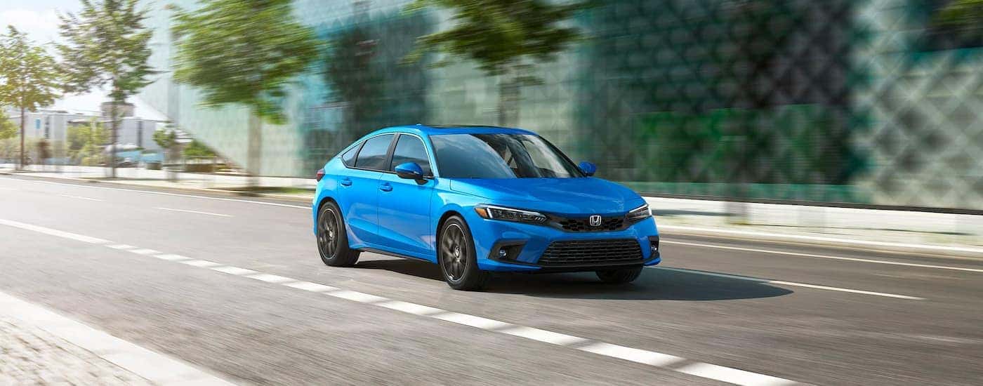 A blue used 2023 Honda Civic Sport Touring driving in a city