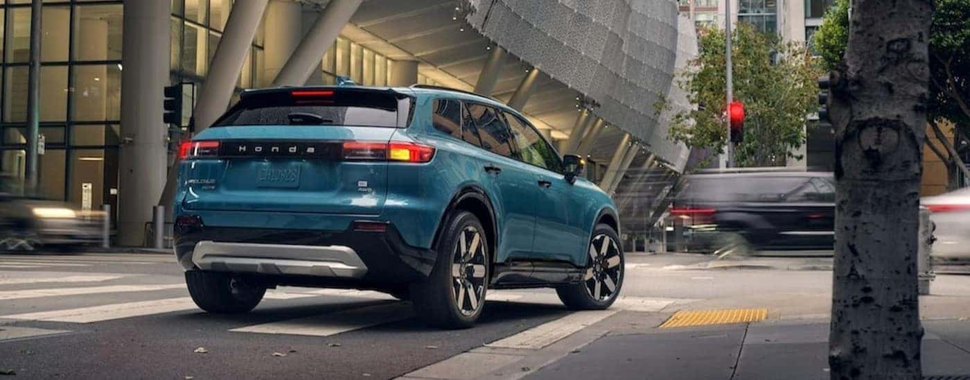 A blue 2025 Honda Prologue driving in a city.