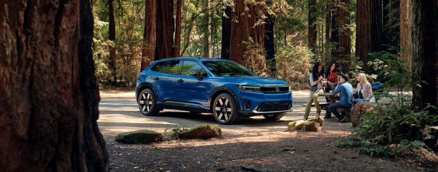 Blue 2025 Honda Prologue Elite for sale parked off-road in a forest.