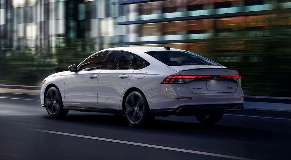 A white 2026 Honda Accord driving down a city street